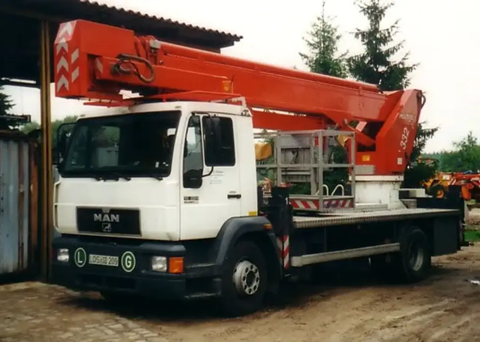 Ein LKW mit einem großen roten Kranaufbau parkt auf einem Bauhof