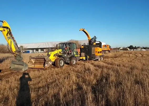 Holzungsarbeiten auf einem Feld mit einem Traktor und Kran