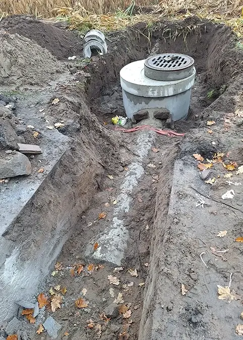 Ein neuer Regenentwässerungsgraben wird an einer kleinen Strasse angelegt