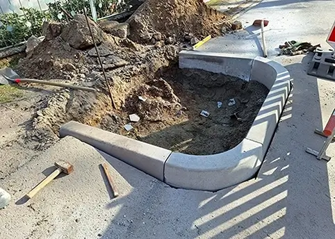 An einer Straße wird eine Begrenzung für ein Entwässerungsgraben gepflastert